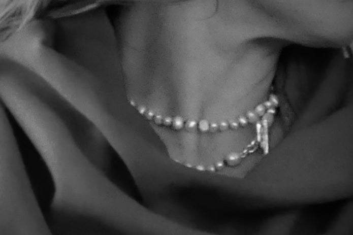 Near black and white close-up of a handmade Amanda Hufford Studio pearl strand necklace on a model's décolletage

