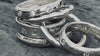 Stack of various handcrafted bands for wedding, ceremony, and celebration. Personalized and set with stones by Amanda Hufford Studio.